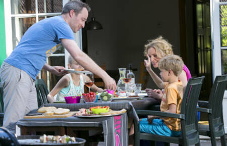 Gezin is aan het eten in de tuin van een vakantiehuis op vakantiepark Roompot Zeebad