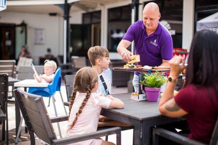 Gezin aan het eten op het terras van vakantiepark Topparken Bospark Ede