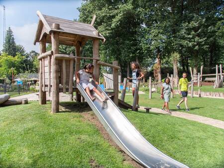 Kind glijdt van de glijbaan in een speeltuin op vakantiepark Topparken Landgoed de Scheleberg