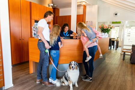 Gezin met hond bij de receptie van vakantiepark Topparken Parc de IJsselhoeve