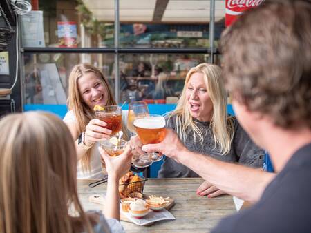 Gezin geniet van een hapje en drankje in het restaurant van Topparken Recreatiepark de Wielerbaan