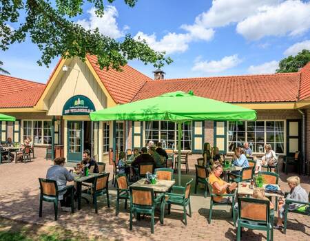 Mensen zitten op het terras van het restaurant van vakantiepark Topparken Resort Veluwe