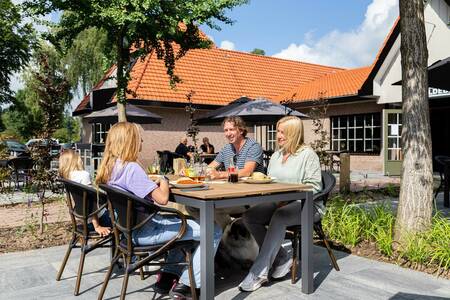Gezin aan het eten op het terras van het restaurant van vakantiepark Topparken Resort Veluwe