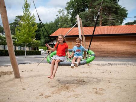Kinderen op een schommel in de speeltuin van vakantiepark Topparken Resort Veluwe