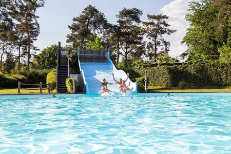 Kinderen glijden van de brede glijbaan in het buitenbad van vakantiepark Topparken Resort Veluwe