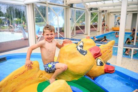 Kind op een speeltoestel in het binnen peuterbad van vakantiepark Topparken Resort Veluwe
