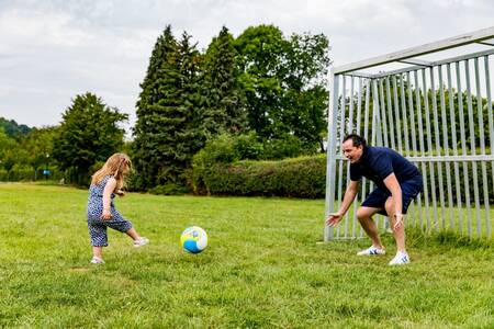 Vader en dochter voetballen op het speelveld van vakantiepark Topparken Résidence Valkenburg
