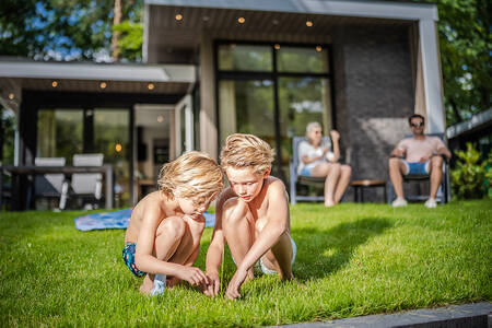 Kinderen spelen in de tuin van een vakantiehuis op vakantiepark De Rimboe en De Woeste Hoogte