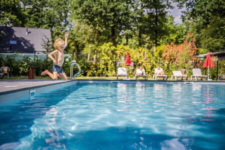 Jongetje springt in het buitenbad van vakantiepark De Rimboe en De Woeste Hoogte