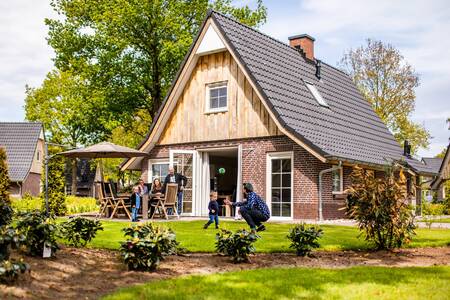 Gezin in de tuin van een vrijstaand vakantiehuis op vakantiepark Villapark Hof van Salland